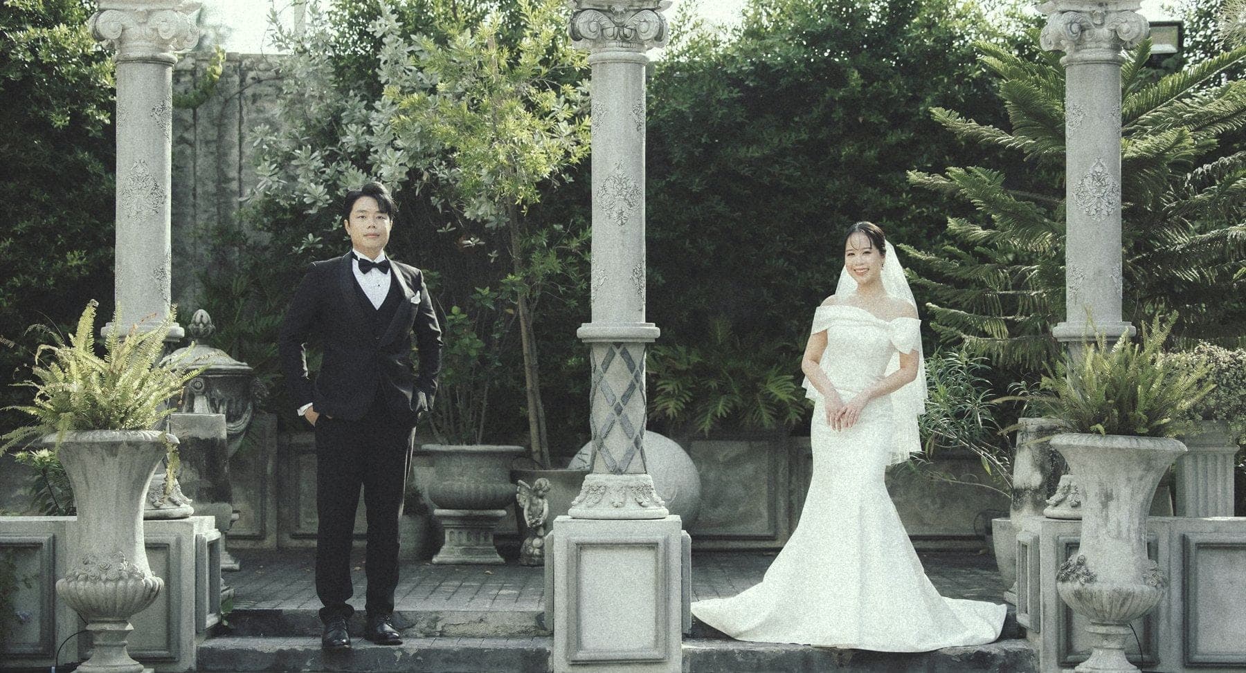Witita and Sorratat standing between stone columns in a garden colonnade